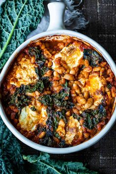 a white dish filled with baked beans and spinach