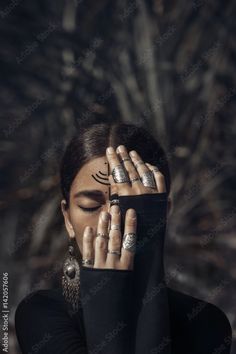 a woman covering her face with her hands and holding her eyes closed to the side