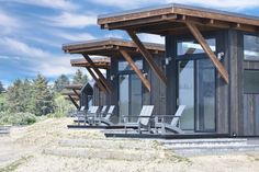 a row of chairs sitting on top of a wooden deck next to a building with windows