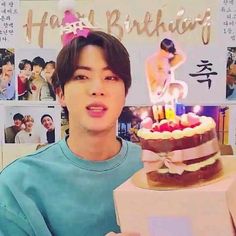 a young man holding a birthday cake with candles on it in front of a poster