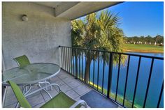 a balcony with table and chairs overlooking the water