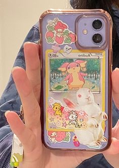 a person holding up a phone case with pokemon stickers on it