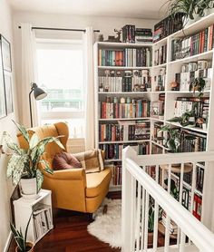 a living room filled with furniture and bookshelves next to a stair case full of books