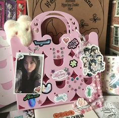 there is a pink purse with pictures and stickers on the front, along with other items