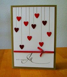 a card with red hearts hanging from strings