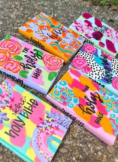 four colorful notebooks with writing on them sitting on top of a stone ground next to flowers