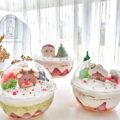 there are three desserts in plastic containers on the table, one is decorated with santa's helpers