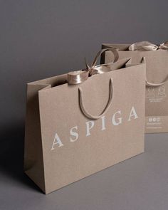 two brown shopping bags with the word aspiga printed on them and tied to each other