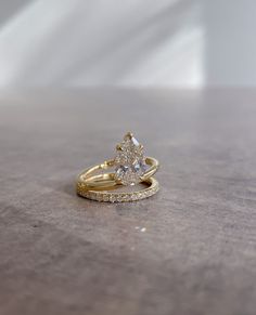 two gold wedding rings on top of each other with one diamond set in the middle