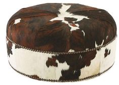 a brown and white cow print ottoman with studded trimmings on the bottom