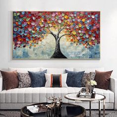 a living room with a white couch and colorful painting on the wall above it's coffee table