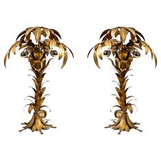 two tall metal sculptures with flowers on each side and leaves on the top, all in gold