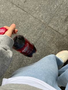 a person sitting on the ground holding onto a soda bottle