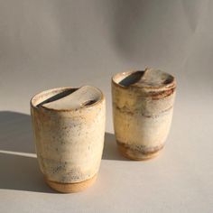 two small cups sitting on top of a white table next to each other, one with brown speckles