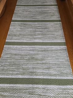 a green and white rug sitting on top of a wooden floor