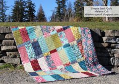 a patchwork quilt sitting on top of a stone wall