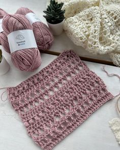 crochet and yarns are on the table next to some potted plants