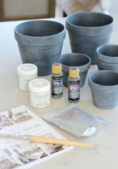 some pots and paint are sitting on a table with other items to decorate the vases