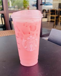 a pink starbucks drink sitting on top of a table