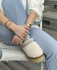 a woman sitting on top of a white chair wearing slippers and holding onto her hand