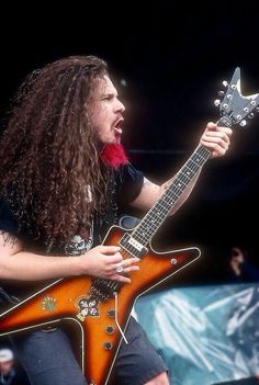 a man with long hair playing an electric guitar