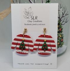 pair of red and white striped christmas sweater earrings with gold tone hooks on display in front of greeting card