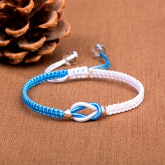 a blue and white bracelet with an arrow on it next to a pinecone