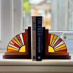 two books are sitting on a window sill next to a stained glass sunburst