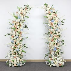 two floral archways with white and blue flowers on the sides, in front of a wall