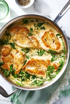 a pan filled with chicken and spinach covered in sauce on top of a table