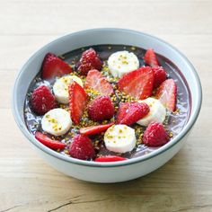 a bowl filled with bananas and strawberries on top of a wooden table