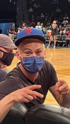 two men wearing face masks sitting on top of a basketball court