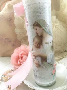 a vase with an image of a woman holding a baby on it next to a pink rose