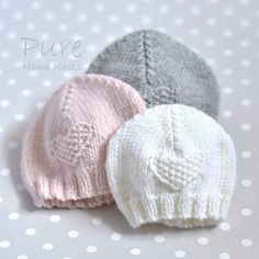 three knitted hats sitting next to each other on a polka dot tablecloth background