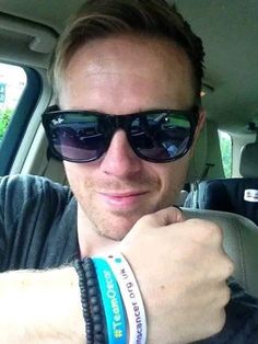 a man wearing sunglasses sitting in the back seat of a car with his arm wrapped around him