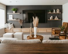 a living room filled with furniture and a flat screen tv mounted on a wall above a wooden coffee table