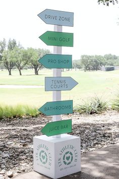 a sign that is on top of a box in the grass with arrows pointing to different locations