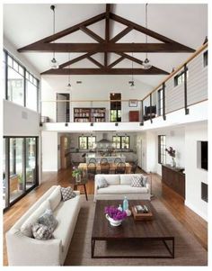 a living room filled with lots of furniture and wooden flooring next to tall windows