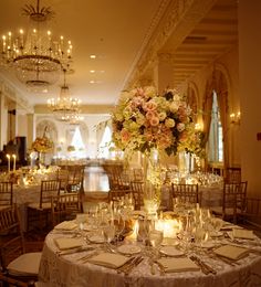 a table set up for a formal function with candles and flowers in vases on the tables