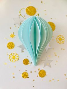 an origami hot air balloon with stars and confetti on the table