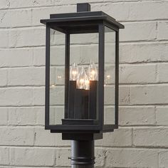 three lit candles are placed in an old - fashioned lantern on the side of a brick wall