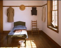 a bed sitting in a bedroom next to a wooden chair and window on top of a hard wood floor