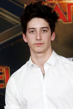 a young man in a white shirt posing for the camera