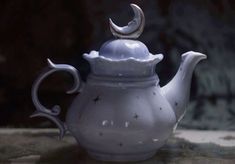 a white tea pot with a crescent decoration on it's top, sitting on a table