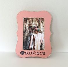 a pink frame with an image of two women in front of trees and the words hazel - nora sisters on it