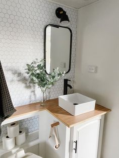 a bathroom with a sink, mirror and toilet paper roll dispenser on the counter