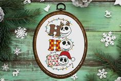 a cross stitch christmas ornament hanging on a wooden background with snowflakes