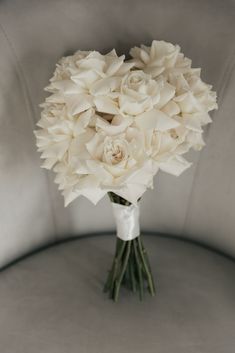 a bouquet of white flowers sitting on top of a gray table next to a wall