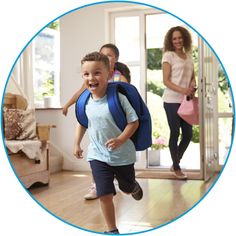 a young boy with a back pack running towards the camera in front of his family