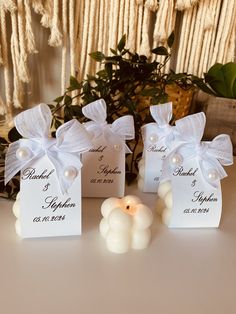 three small white candles sitting on top of a table next to some cards with names